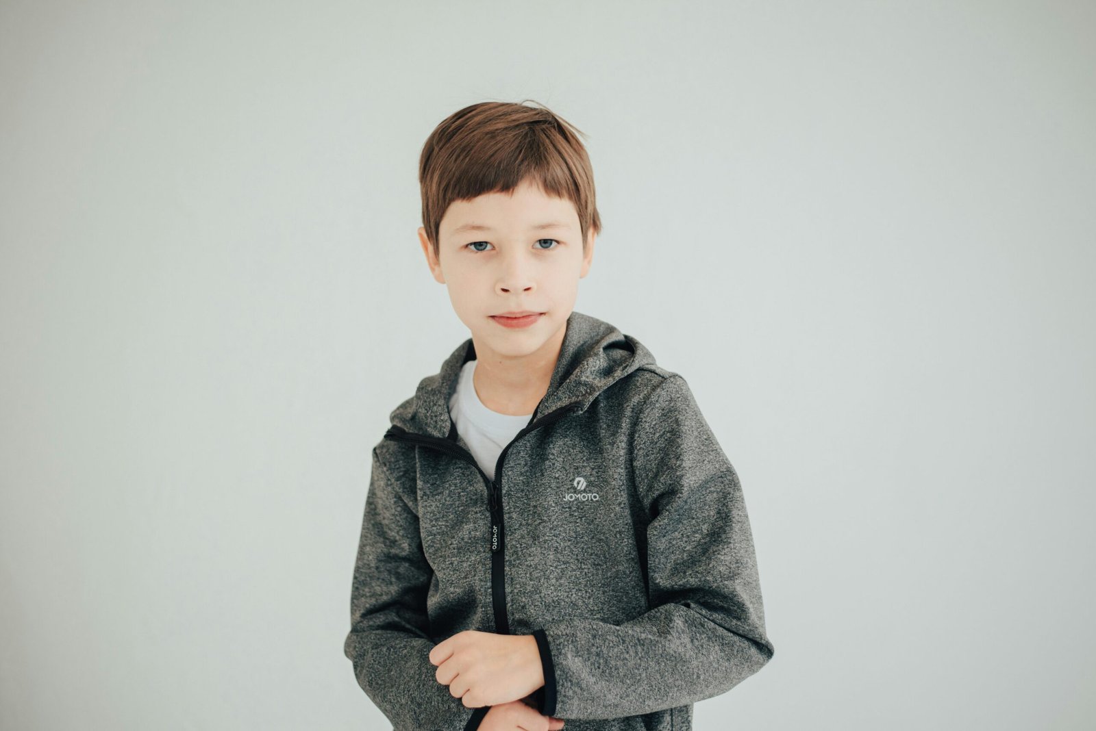 Charming portrait of a young boy in a gray jacket, looking confidently at the camera.