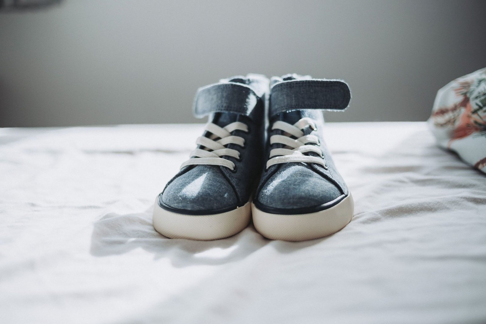 Close-up of trendy denim sneakers on a bed, perfect for fashion enthusiasts.
