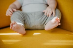 Cute baby feet and hands on a sunny yellow chair, evoking warmth and innocence.