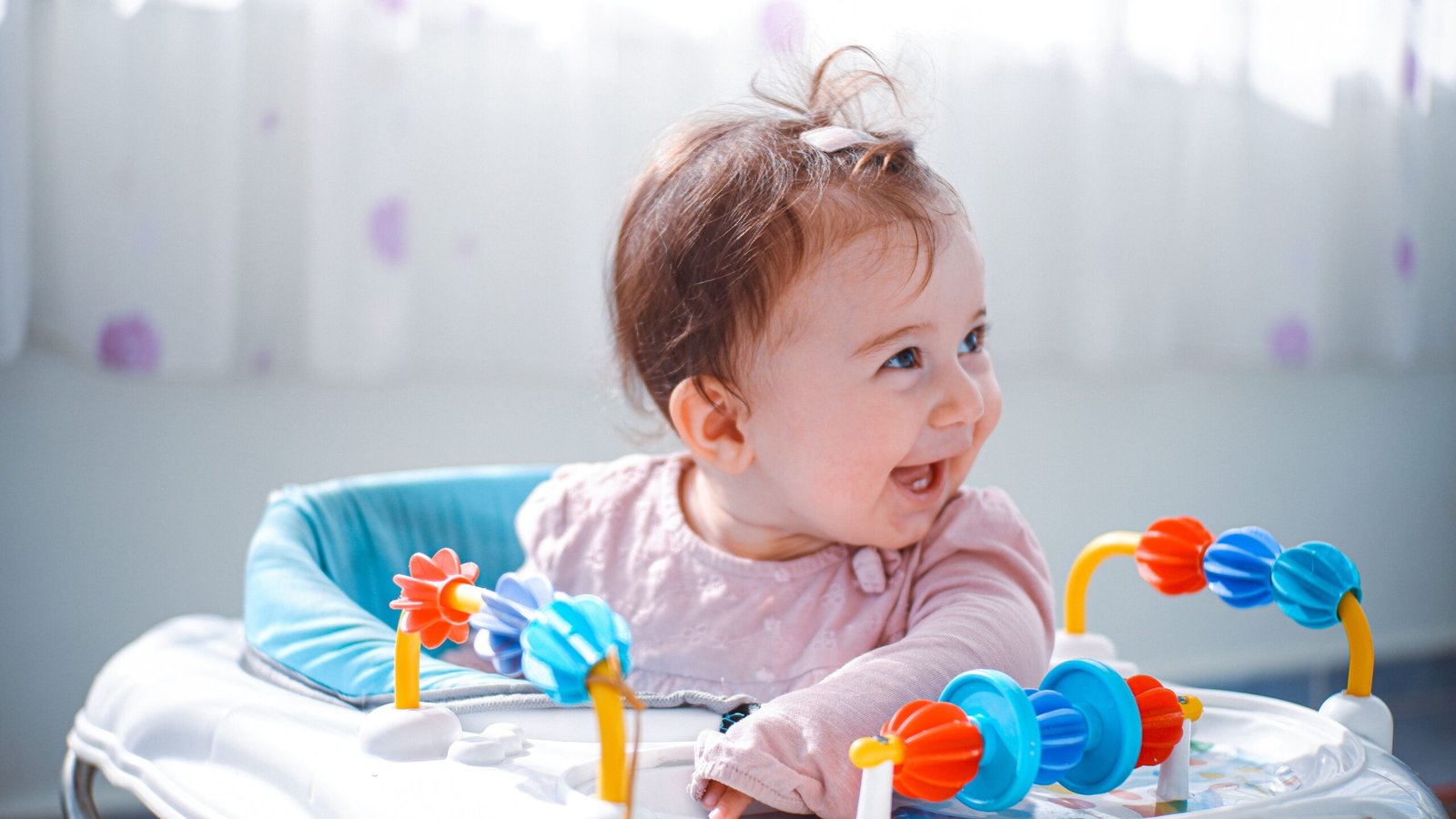 A happy baby plays with a colorful toy indoors, showcasing joy and curiosity.