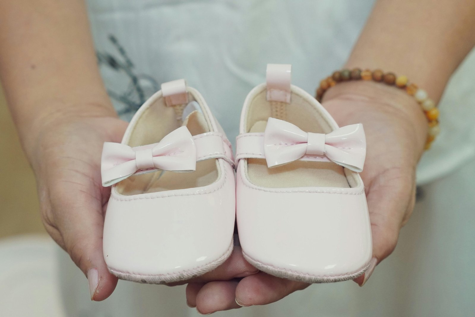 pexels photo 37621032 37621032 Adorable baby shoes with bows held in hands, perfect for a baby girl announcement or gift idea.