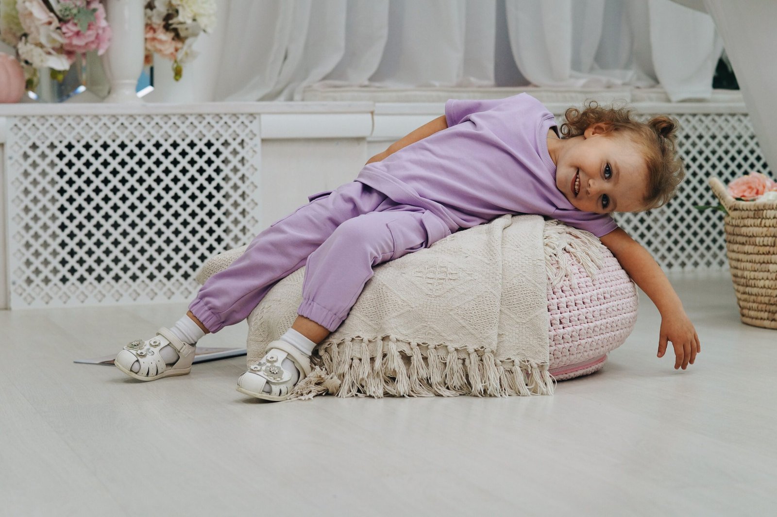 Happy young child in purple outfit reclining on a cushion indoors, exuding innocence and joy.